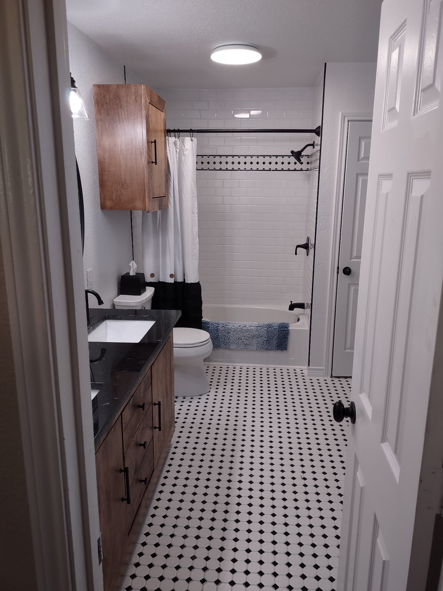 Black-and-white bathroom with tiled tub surround and wood vanity