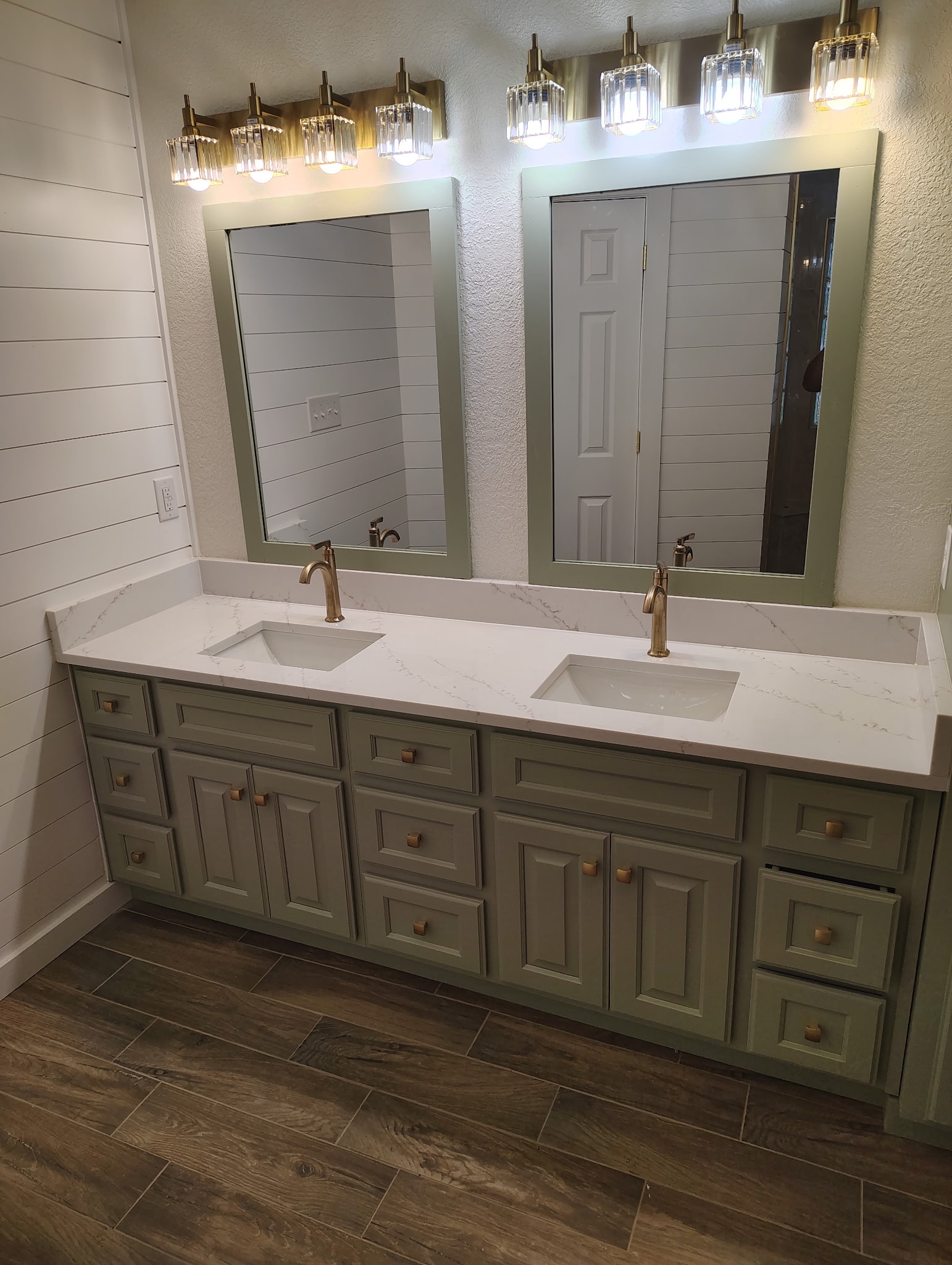 Green double vanity with framed mirrors and brass-tone fixtures