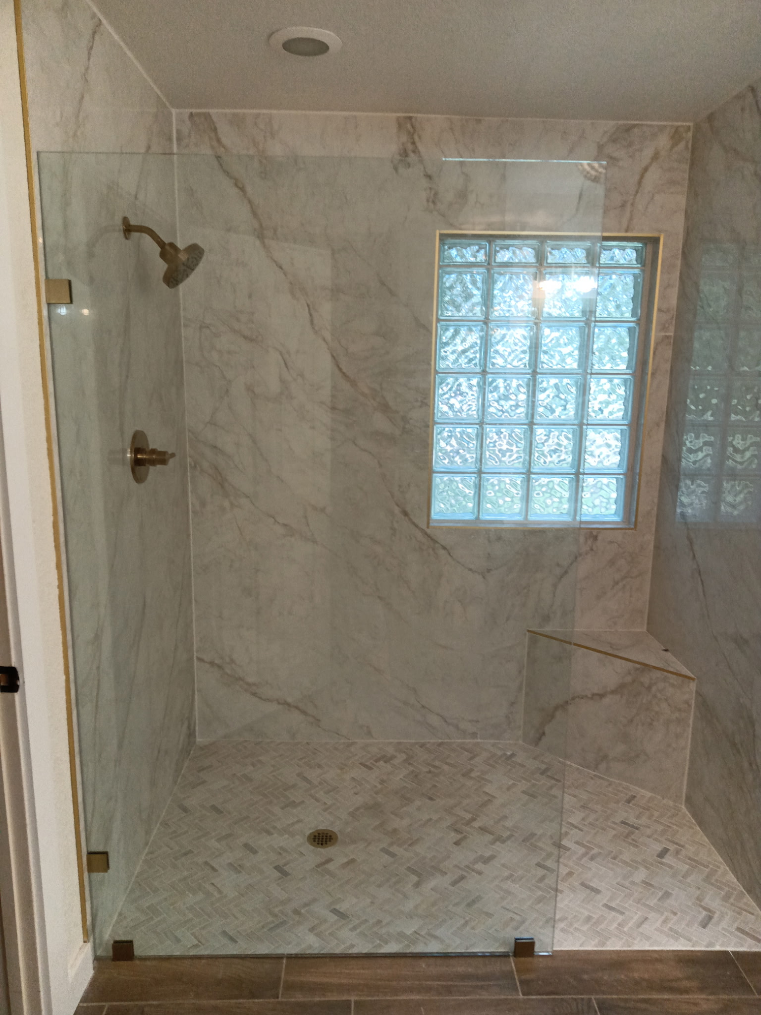 Walk-in shower with porcelain slab walls and corner bench